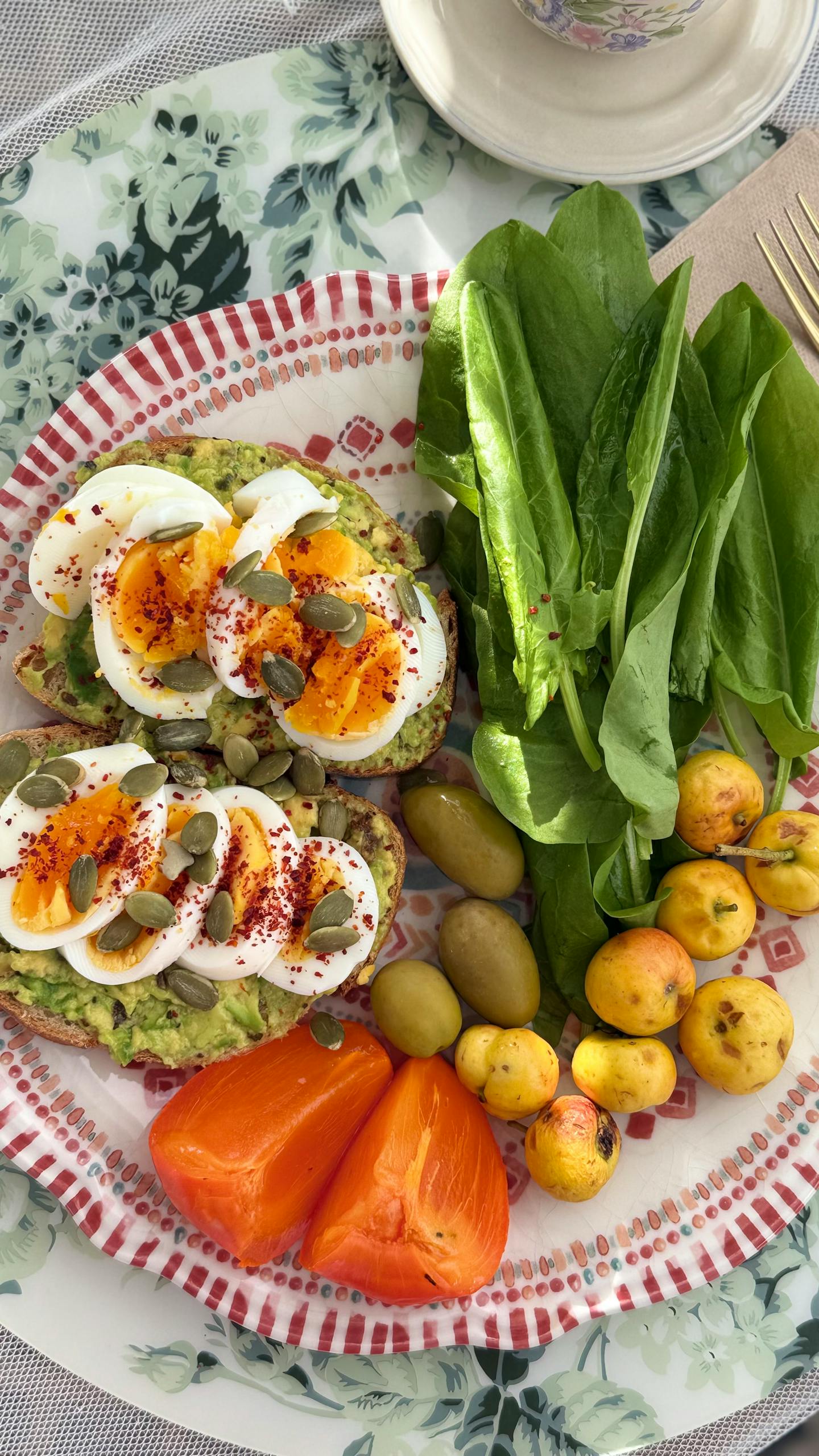 Delicious avocado toast with boiled eggs, fresh greens, and assorted vegetables for a nutritious breakfast.